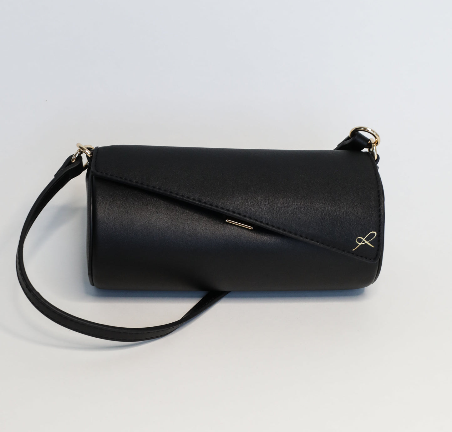 Cylinder Shaped Handbag in the color Black. Bag shown with short strap